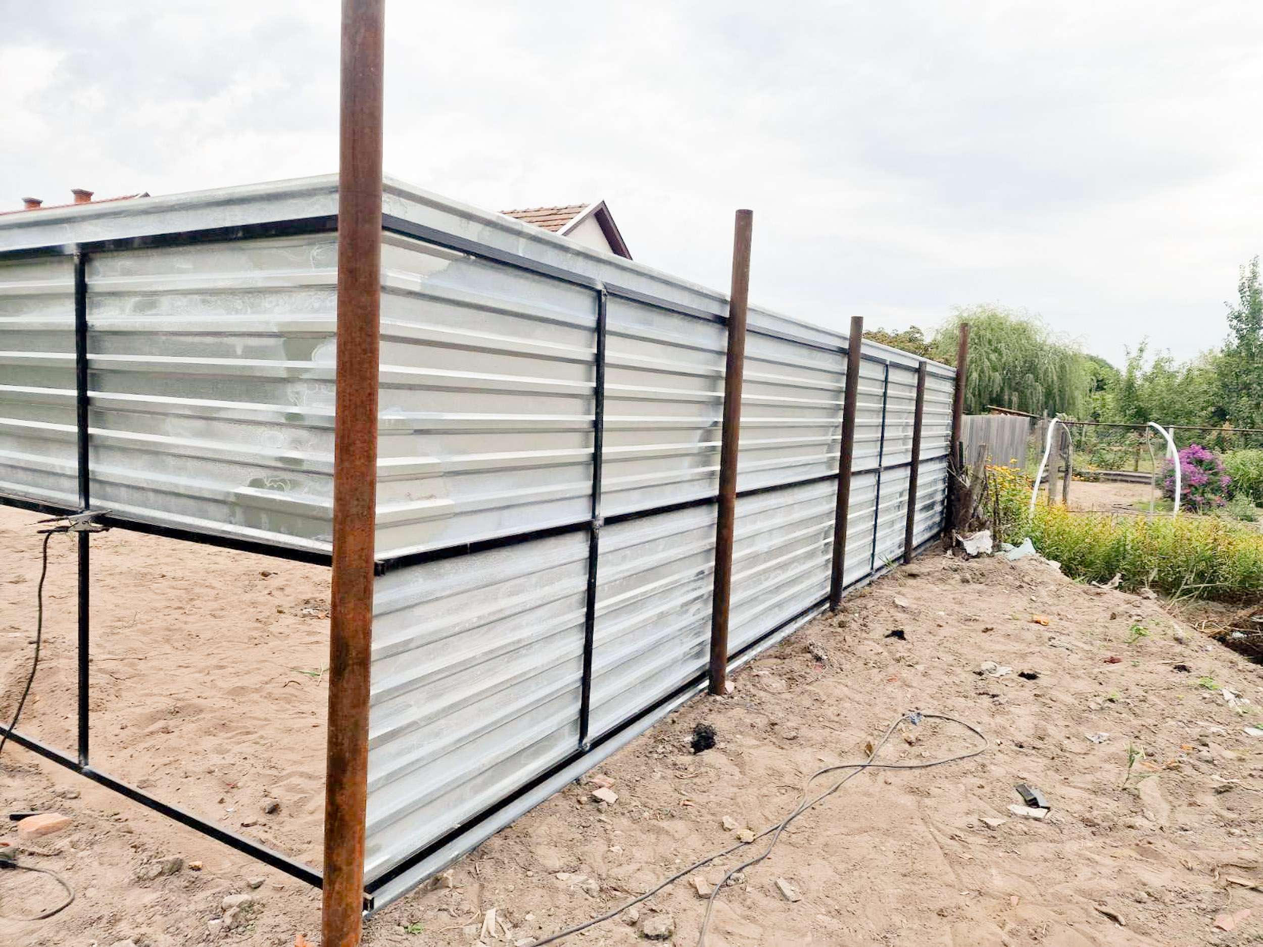 Trapézlemez kerítés építése – fehér lemez fém vázszerkezeten