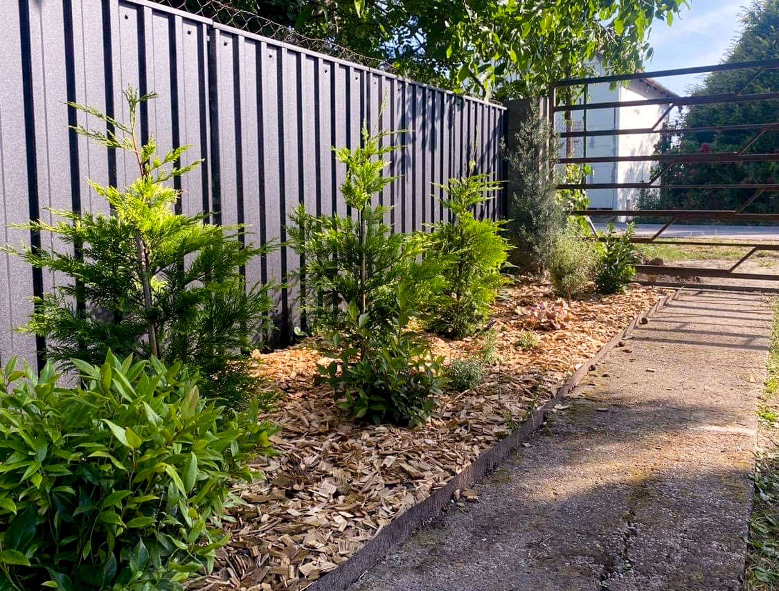 Szürke trapézlemez kerítés kertben – oldalnézet